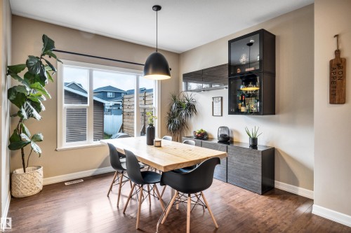 Hardwood-style flooring, large window, pendant lighting, wall-mounted display cabinetry, and built-in credenza - 337 Southfork Drive, Leduc, AB 