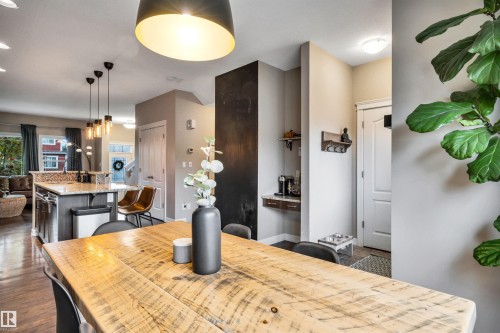 Open-concept living area featuring wood-finish flooring, a kitchen island with stone countertops and mosaic tile backsplash, and built-in entry shelving - 337 Southfork Drive, Leduc, AB 