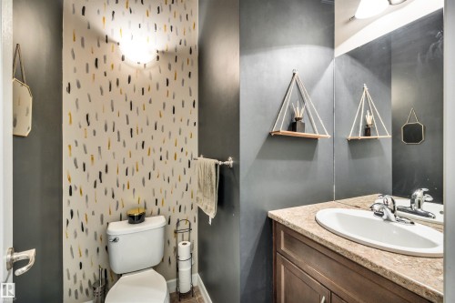 Powder room with a single vanity, undermount sink, built-in cabinetry, and wall-mounted lighting - 337 Southfork Drive, Leduc, AB 