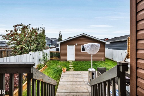 Expansive backyard featuring a wood deck, wood-finish stairs, a detached accessory dwelling unit with brown siding, and a white picket fence - 337 Southfork Drive, Leduc, AB 