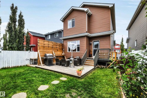 Expansive backyard featuring a manicured lawn, a multi-level wood deck, a privacy fence, and concrete stepping stones - 337 Southfork Drive, Leduc, AB 