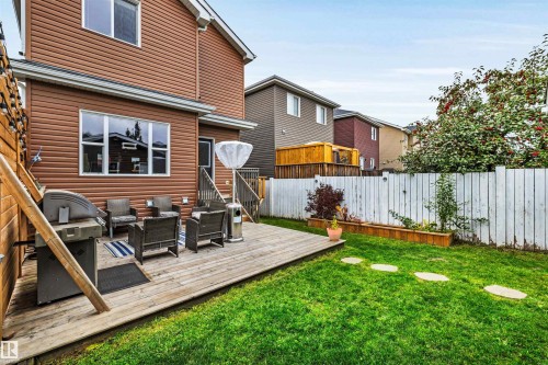 Expansive backyard featuring a wood deck, manicured lawn, and raised garden beds - 337 Southfork Drive, Leduc, AB 