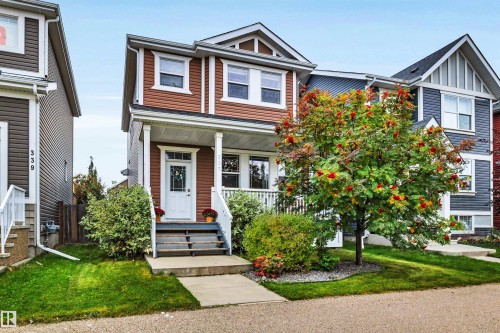 Front exterior featuring brown horizontal siding, white trim, a covered porch with white railings, and a concrete walkway - 337 Southfork Drive, Leduc, AB 