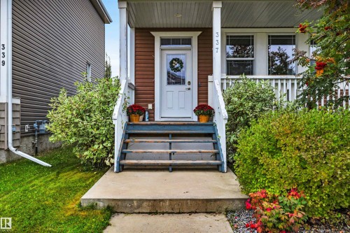 Front entry with a white door, framed by a porch featuring white railings and supporting columns - 337 Southfork Drive, Leduc, AB 