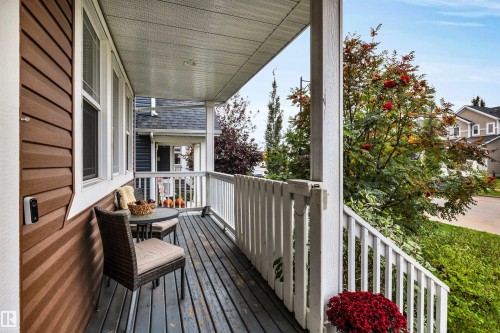 Covered porch with wood-finish decking, white railings, and brown horizontal siding - 337 Southfork Drive, Leduc, AB 