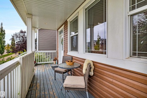 Covered front porch with white railings, brown siding, and multiple windows - 337 Southfork Drive, Leduc, AB 