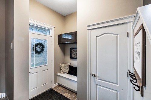 Entryway featuring a white paneled door with decorative glass, transom window, built-in bench, and a built-in wall shelf - 337 Southfork Drive, Leduc, AB 