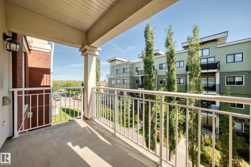 Private balcony with concrete flooring, white metal railing, and an exterior wall light fixture - #307 1003 Gault Bv Nw, Edmonton, AB 