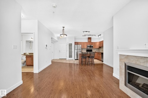 Hardwood-finish flooring, kitchen with stainless steel appliances, breakfast bar, fireplace with tile surround, and built-in cabinetry - #307 1003 Gault Bv Nw, Edmonton, AB 