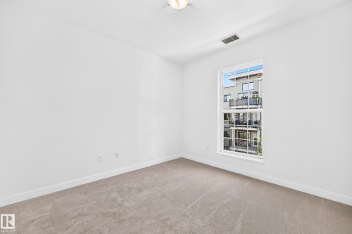 Light-filled room featuring neutral carpeting and a large window - #307 1003 Gault Bv Nw, Edmonton, AB 