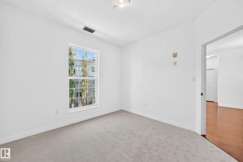 Single-hung window with white trim, light gray carpeting, and white painted walls - #307 1003 Gault Bv Nw, Edmonton, AB 