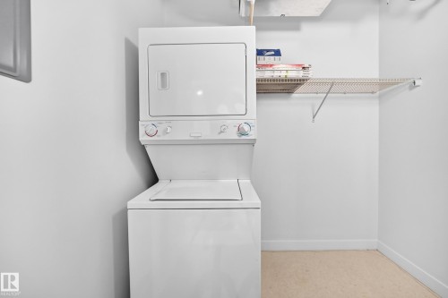 Stacked white washer and dryer, wire shelving, and light-toned flooring - #307 1003 Gault Bv Nw, Edmonton, AB 