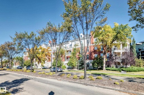 Red brick and white facade building with multiple balconies, dormer windows, and architectural detailing - #307 1003 Gault Bv Nw, Edmonton, AB 