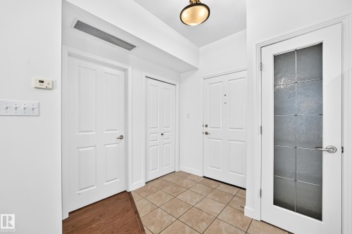 Foyer featuring tile flooring, white paneled doors, and a decorative glass interior door - #307 1003 Gault Bv Nw, Edmonton, AB 
