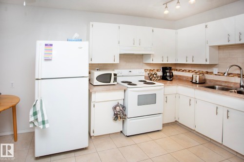 White cabinetry and appliances, tile flooring, and track lighting - #407 9810 178 St Nw, Edmonton, AB 