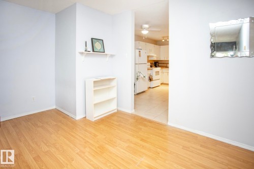 Wood-finish flooring throughout, with a built-in wall shelf and an open-concept kitchen - #407 9810 178 St Nw, Edmonton, AB 