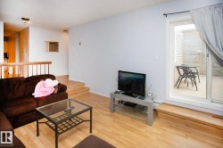 Hardwood-style flooring throughout, sliding glass door to an outdoor patio, and a staircase with a wooden railing - 