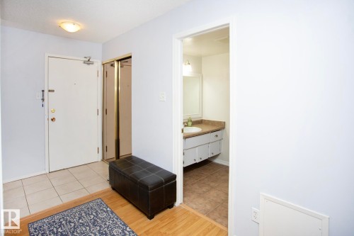 Entryway featuring a white door, tile flooring, and closet with sliding mirrored doors - #407 9810 178 St Nw, Edmonton, AB 