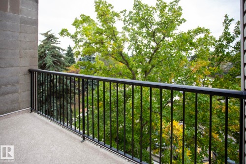 Outdoor balcony with black metal railing, concrete block wall, and textured flooring - #407 9810 178 St Nw, Edmonton, AB 