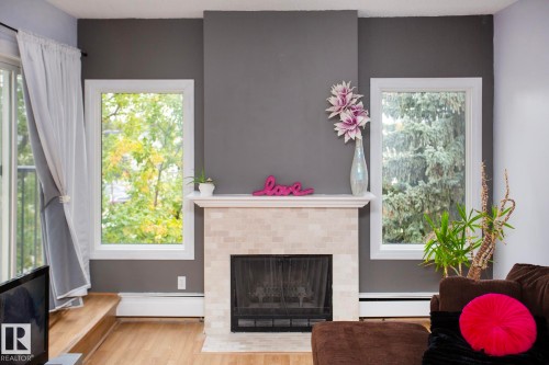 Fireplace featuring a stone tile surround and white mantel - #407 9810 178 St Nw, Edmonton, AB 