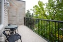 Outdoor balcony featuring a textured concrete floor, black metal railing, and a wall of concrete blocks - #407 9810 178 St Nw, Edmonton, AB 