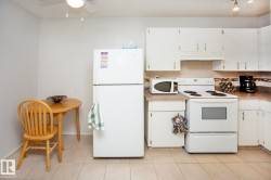 Kitchen featuring white cabinetry, light-colored countertops, tile backsplash, and tile flooring - 