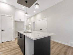 Kitchen island with a waterfall edge countertop, undermount stainless steel sink, and a high-arc faucet - 