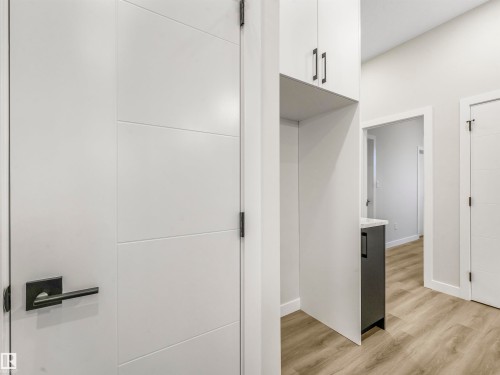 White panel doors with matte black hardware, wood-finish flooring, and light gray cabinetry with coordinating hardware - 36 Dalquist Bay, Leduc, AB 
