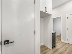 White panel doors with matte black hardware, wood-finish flooring, and light gray cabinetry with coordinating hardware - 