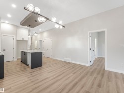 Open-concept layout with light wood-finish flooring, recessed lighting, and a kitchen island featuring a light-colored countertop - 