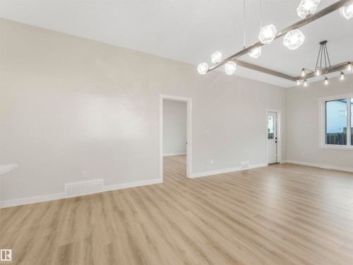 Spacious interior with wood-finish flooring, white walls, and a recessed doorway - 36 Dalquist Bay, Leduc, AB 