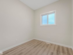 Wood-finish flooring with light-toned walls and a single window - 