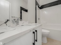 White vanity with integrated dual sinks, chrome fixtures, and matte black hardware - 