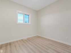 Light wood-finish flooring, white walls, and a white-framed window - 
