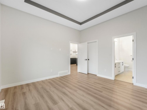 Vaulted ceiling with tray detail, wood-finish flooring, white trim, and doors with dark hardware - 36 Dalquist Bay, Leduc, AB 