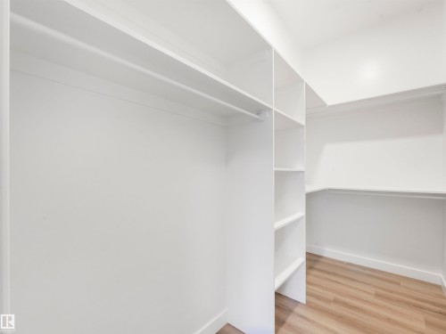 Custom closet system featuring shelving, hanging rods, and wood-finish flooring - 36 Dalquist Bay, Leduc, AB 