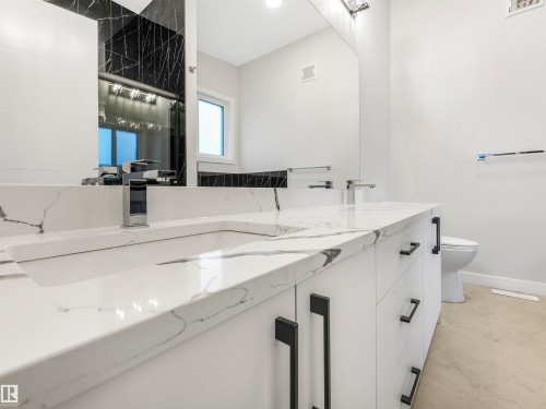 Dual vanity featuring white cabinetry, integrated sinks, chrome faucets, and stone countertops - 36 Dalquist Bay, Leduc, AB 