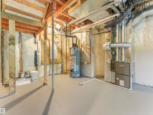 Unfinished basement with exposed wooden beams, painted concrete flooring, and visible insulation - 36 Dalquist Bay, Leduc, AB 
