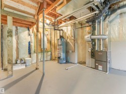 Unfinished basement with exposed wooden beams, painted concrete flooring, and visible insulation - 