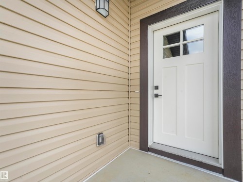 White paneled entry door with clear glass lites and dark hardware - 36 Dalquist Bay, Leduc, AB 