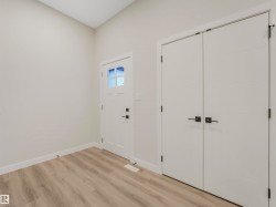 Vaulted ceiling with light-toned walls, wood-finish flooring, and white trim - 