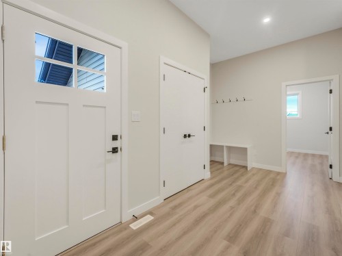 Entryway featuring wood-finish flooring, a built-in bench, and a modern front door with divided lites - 36 Dalquist Bay, Leduc, AB 