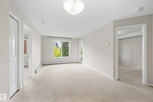 Neutral wall color, light-toned carpet, multiple doorways, and a window with exterior visibility - #215 11804 22 Av Sw, Edmonton, AB 