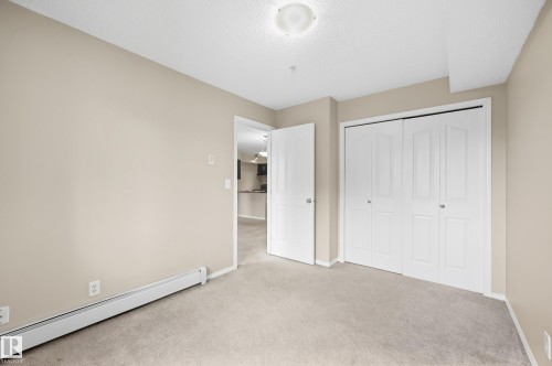 Neutral-toned walls, carpeted flooring, and a flush mount ceiling light fixture - #215 11804 22 Av Sw, Edmonton, AB 