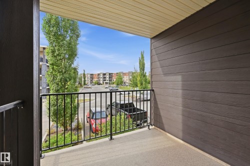 Balcony with textured concrete flooring, dark horizontal siding, and a black metal railing - #215 11804 22 Av Sw, Edmonton, AB 