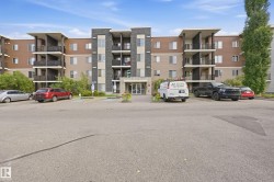 Multi-story building featuring balconies, a prominent main entrance, and exterior finishes including stone-look siding and horizontal panels - 
