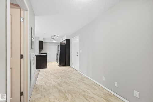Tile flooring, track lighting, dark wood-finish cabinetry, and stainless steel appliances - #215 11804 22 Av Sw, Edmonton, AB 