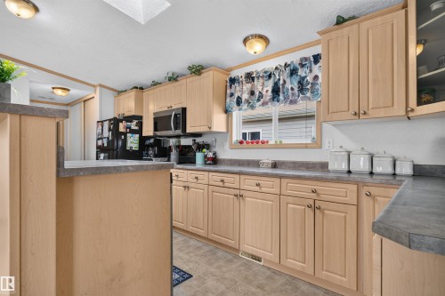 Light wood-finish cabinetry with silver-tone hardware, dark countertops, and a built-in microwave - 1405 53222 Range Road 272, Rural Parkland County, AB 