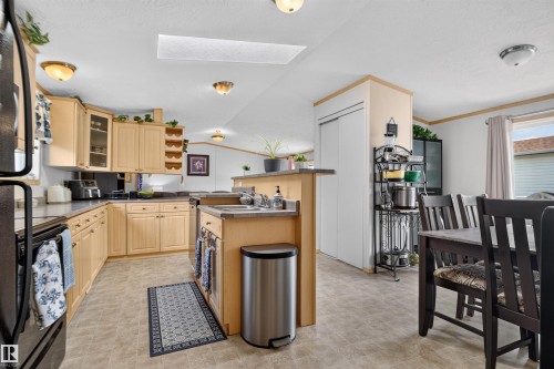 Kitchen with light wood-finish cabinetry, dark countertops, a skylight, and an integrated dining area - 1405 53222 Range Road 272, Rural Parkland County, AB 