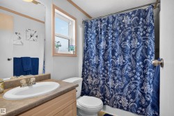 Vanity with an oval sink, light wood-finish cabinetry, and a window with wood trim - 